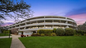 A multi-story building with a circular design, featuring multiple balconies and a well-maintained lawn in front. - Bright 2-bed With Private Balcony (Canberra)