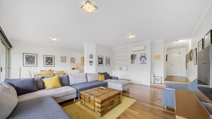 A modern living room with a sofa set, a wooden coffee table, and a television. - Bright 2-bed With Private Balcony (Canberra)