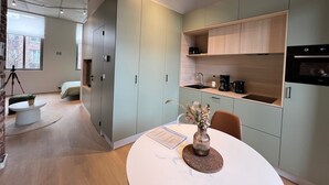 A modern kitchen with built-in appliances, a dining area with a table and chairs, and a large window providing natural light. - Amazing Apartment in Bree With Terrace (Bons Villers)