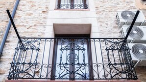 A building with a stone facade, a balcony with wrought iron railings, and air conditioning units on the exterior wall. - Cal Vientos (Paüls)