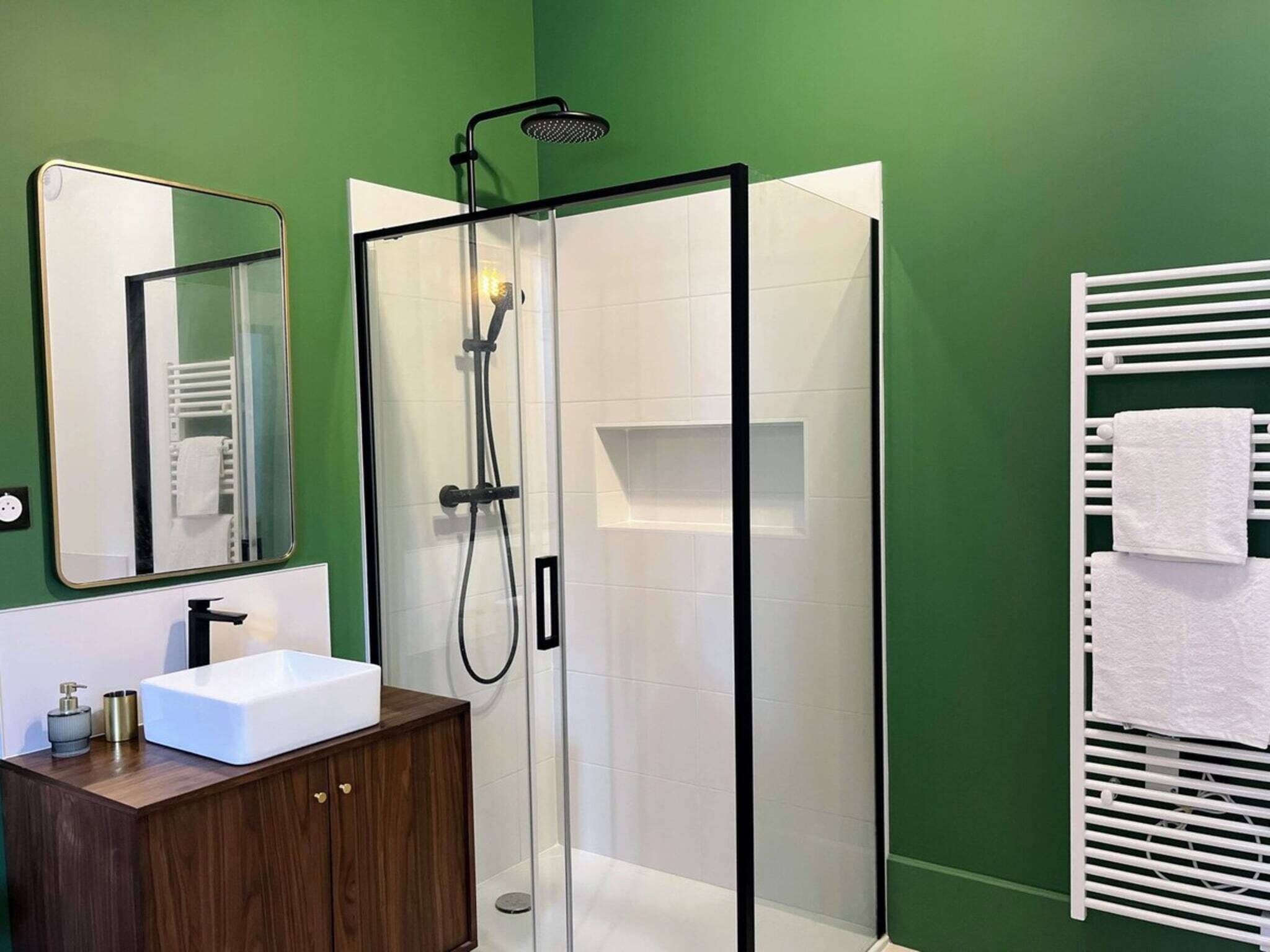 A modern bathroom with a glass-enclosed shower, a white sink, and a wooden vanity.