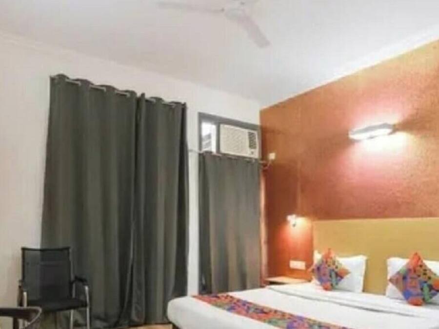 A hotel room with a bed, a desk, a chair, and a wardrobe.
