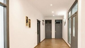 A hallway with wooden flooring, grey doors, and white walls. - royal spark inn03 (Gurugram)