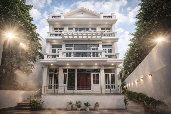 A multi-story building with a grand entrance, a staircase, and a series of potted plants. - royal spark inn03 (Gurugram)