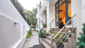 A narrow pathway leading to a building with a staircase and potted plants. - royal spark inn03 (Gurugram)