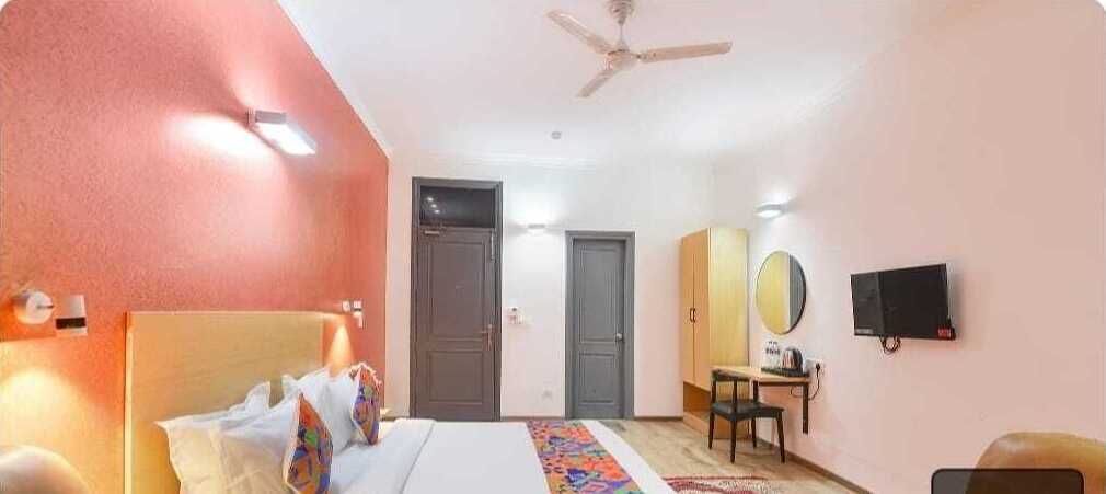 A hotel room with a bed, a desk, a chair, a television, and a ceiling fan.