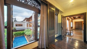 A room with a large window, wooden flooring, and a view of a swimming pool and neighboring buildings. - At Tree Hotel Thaphae Gate Chiangmai (Chiang Mai)