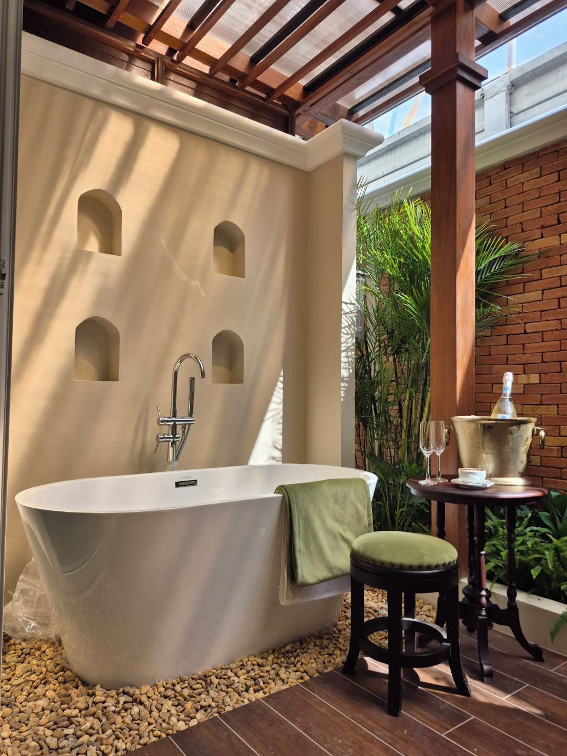 Une salle de bain moderne avec une baignoire sur pieds, un petit tabouret et une table avec une boisson et un verre.