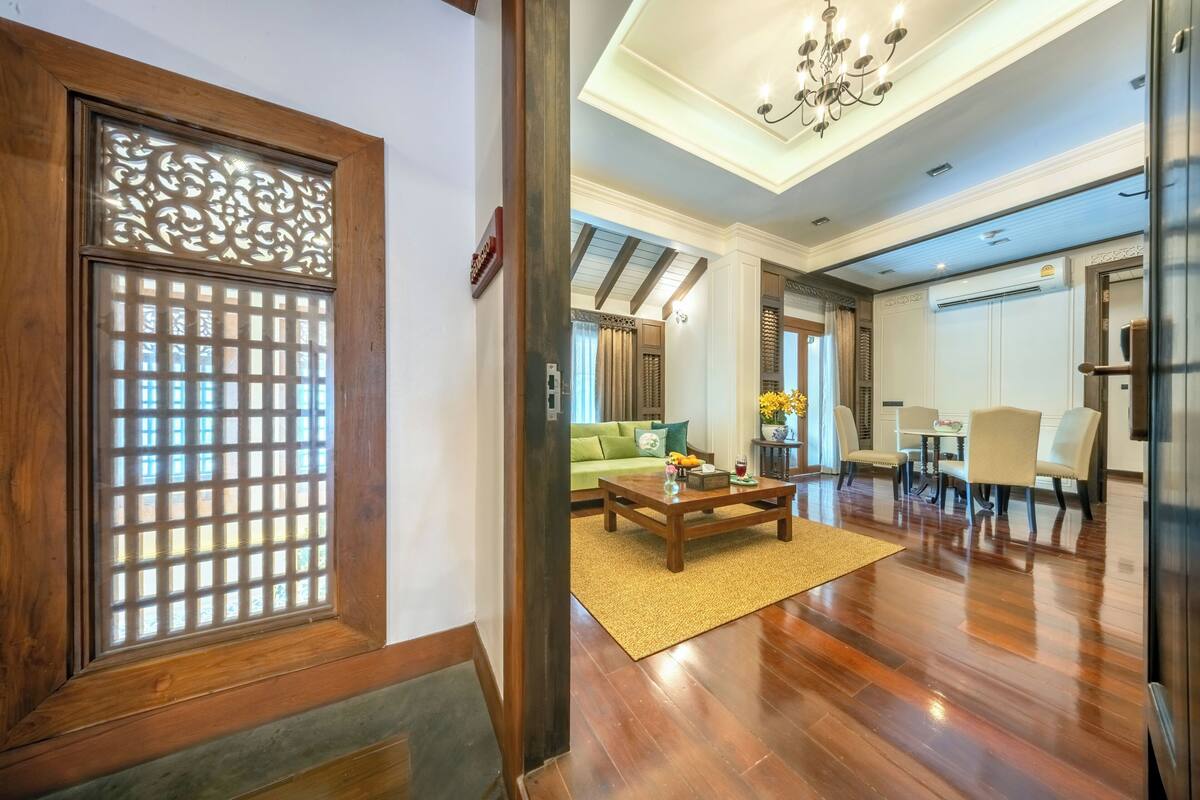 Un intérieur moderne avec un plancher en bois, un canapé vert, une table basse et un coin repas comprenant des chaises et une table.