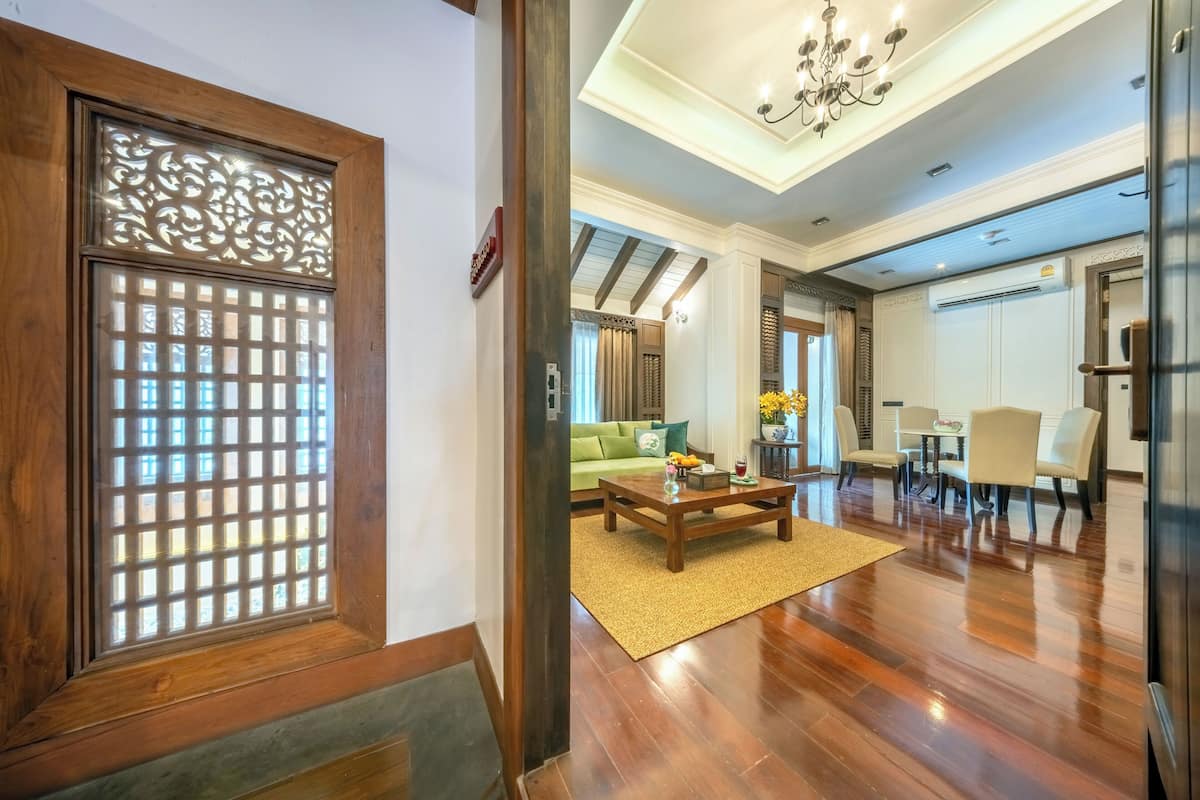 A modern interior with a wooden floor, a green sofa, a coffee table, and a dining area with chairs and a table.