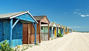 A row of beach huts with a sandy path leading to the beach. - Coastal Home for 6 in The Witterings (Chichester)