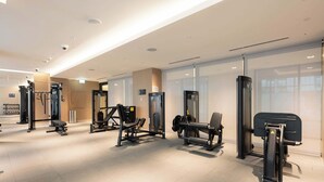 Ein modernes Fitnessstudio mit verschiedenen Trainingsgeräten, einer Bank und Kurzhanteln.