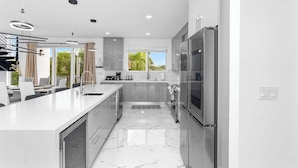 A modern kitchen with a central island, stainless steel appliances, and a large window providing natural light. - Isla Luna Waterfront Oasis Pool Dock Kayaks (Marathon)