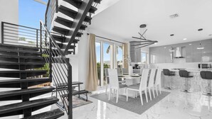 A modern kitchen with a dining area, a staircase, and large windows. - Isla Luna Waterfront Oasis Pool Dock Kayaks (Marathon)