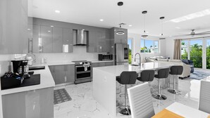 A modern kitchen with a central island, stainless steel appliances, and a large window overlooking greenery. - Isla Luna Waterfront Oasis Pool Dock Kayaks (Marathon)