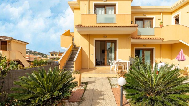 A two-story building with a balcony, a staircase, and a patio area with outdoor furniture. - In a Residence With a Private Patio and air Conditioning (Castelsardo)