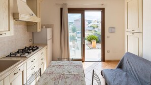 A compact kitchen with a gas stove, cabinets, and a view of the outside. - In a Residence With a Private Patio and air Conditioning (Castelsardo)