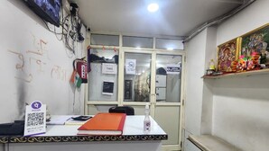 Una mesa de recepción con un cartel que indica la hora de salida, un código QR y una pequeña estantería con objetos.
