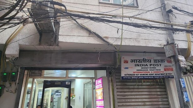 Un edificio con un letrero de India Post y una puerta con persiana cerrada.