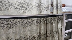 Una habitación con literas, una ventana de metal y un cortin con estampado de hojas.