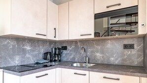 A modern kitchen with a built-in oven, a coffee maker, and a sink. - Charming 2-person Apartment Located Near the Center (De Koog)