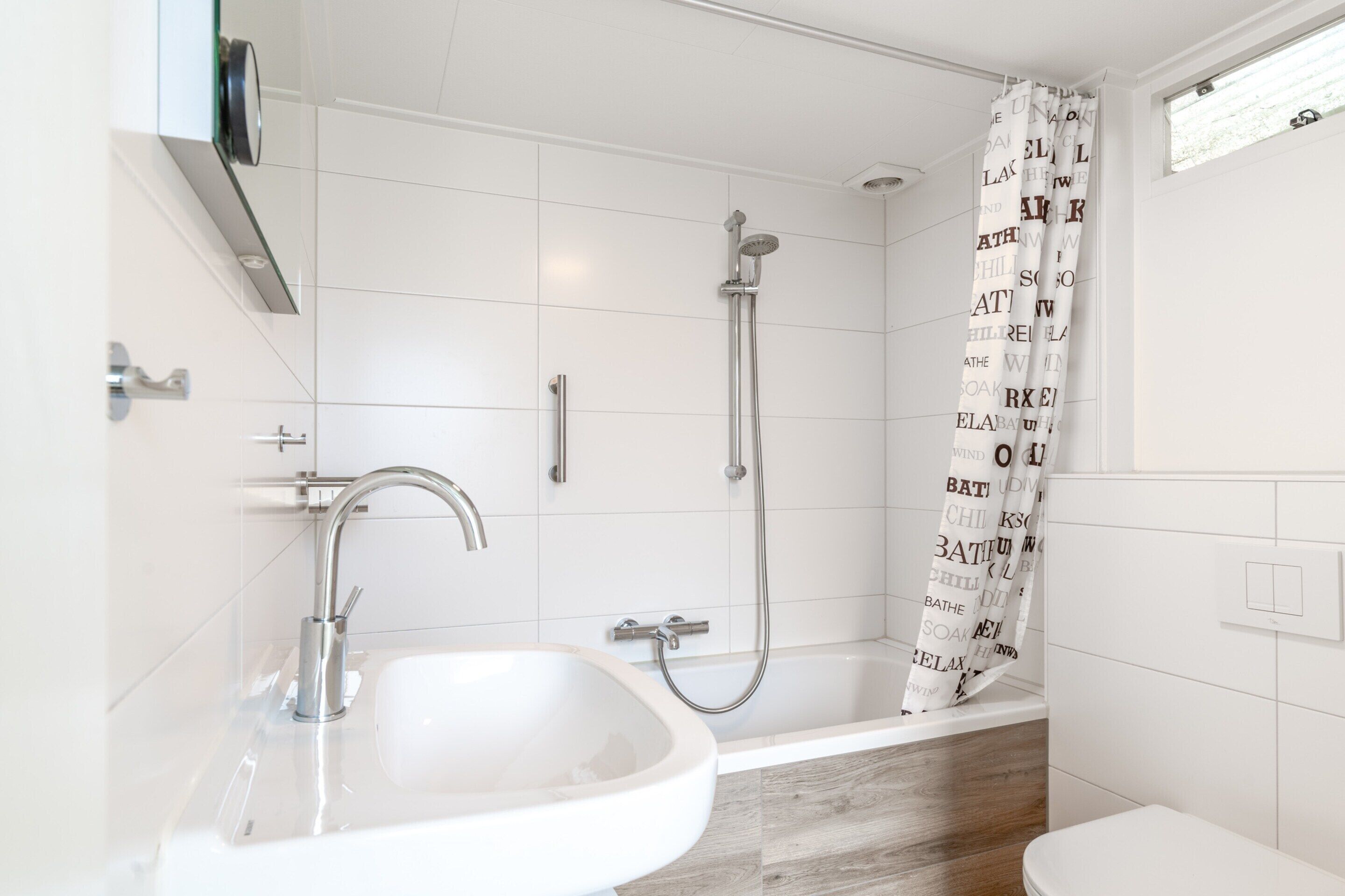 Een moderne badkamer met een wit wastafel, een badkuip en een douche.