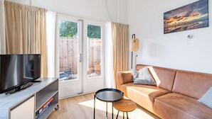 A living room with a sofa, TV, and a small table. - Charming 2-person Apartment Located Near the Center (De Koog)