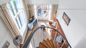 A spacious living area with a staircase, large windows, and a view of the outdoors. - Charming 2-person Apartment Located Near the Center (De Koog)