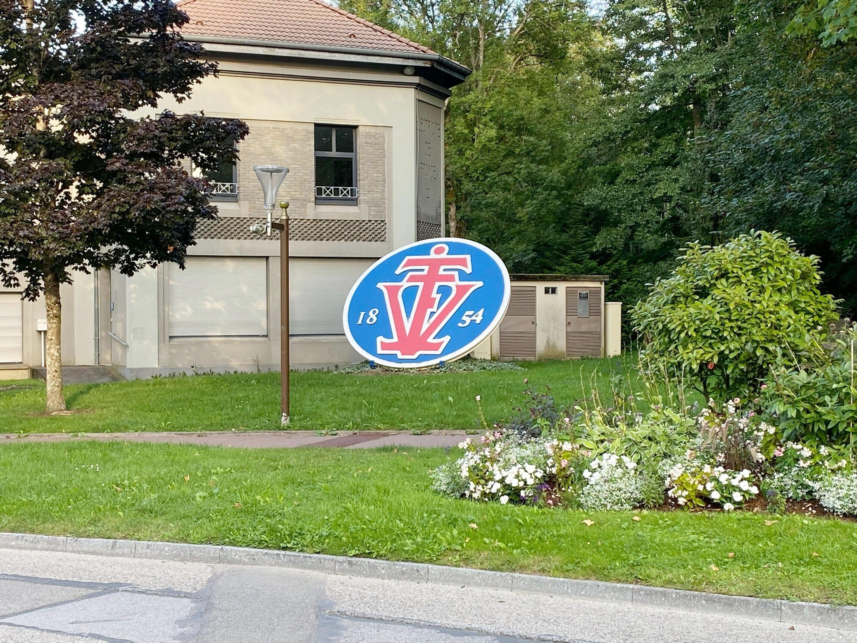 En bygning med et blåt og hvidt skilt, der viser et rødt 'V' og tallene '18' og '54'.