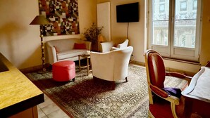 A living room with a sofa, armchair, ottoman, and a flat-screen TV mounted on the wall. - Amazing Holiday Home in the Heart of Vittel (Vittel)