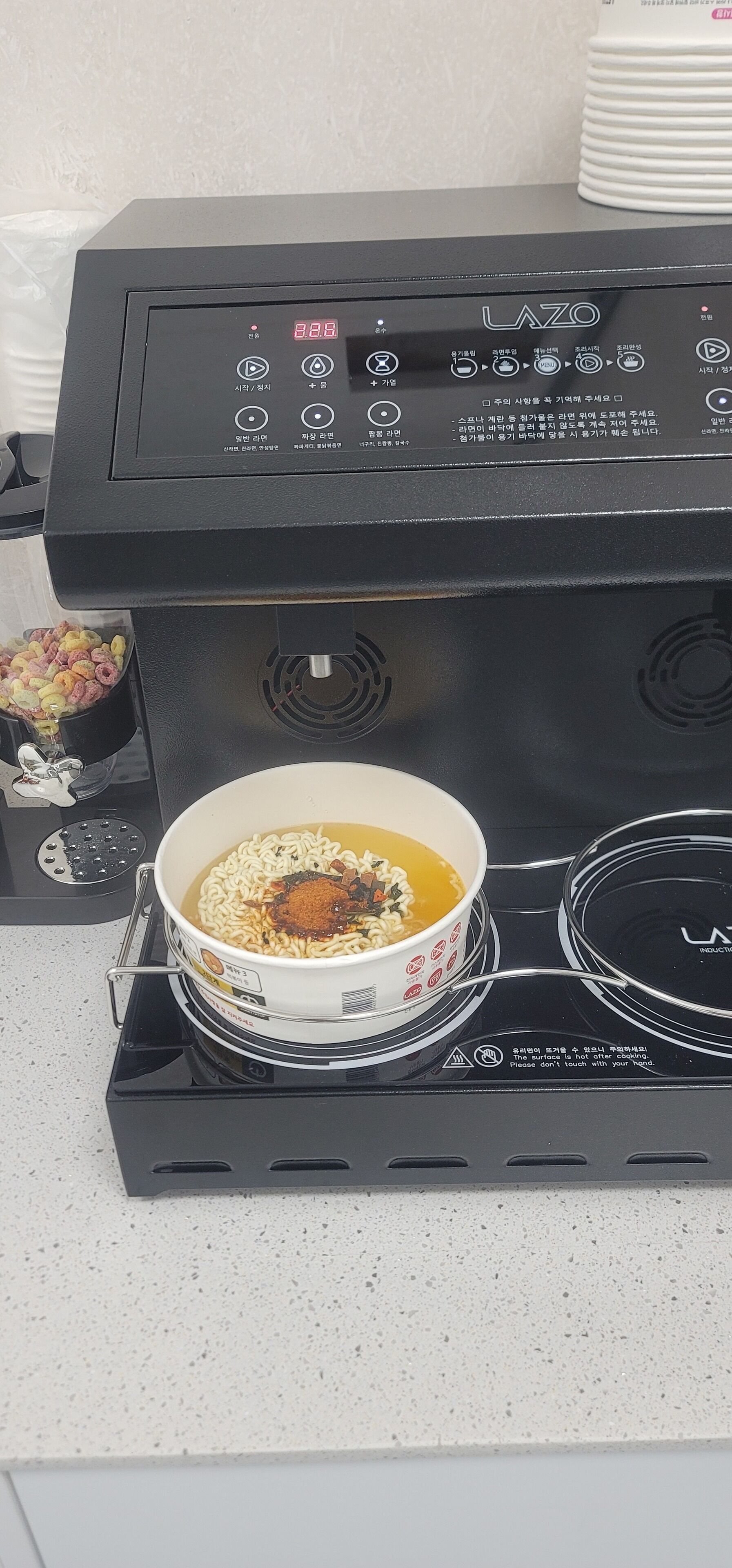 A kitchen stove with a bowl of instant noodles on it.