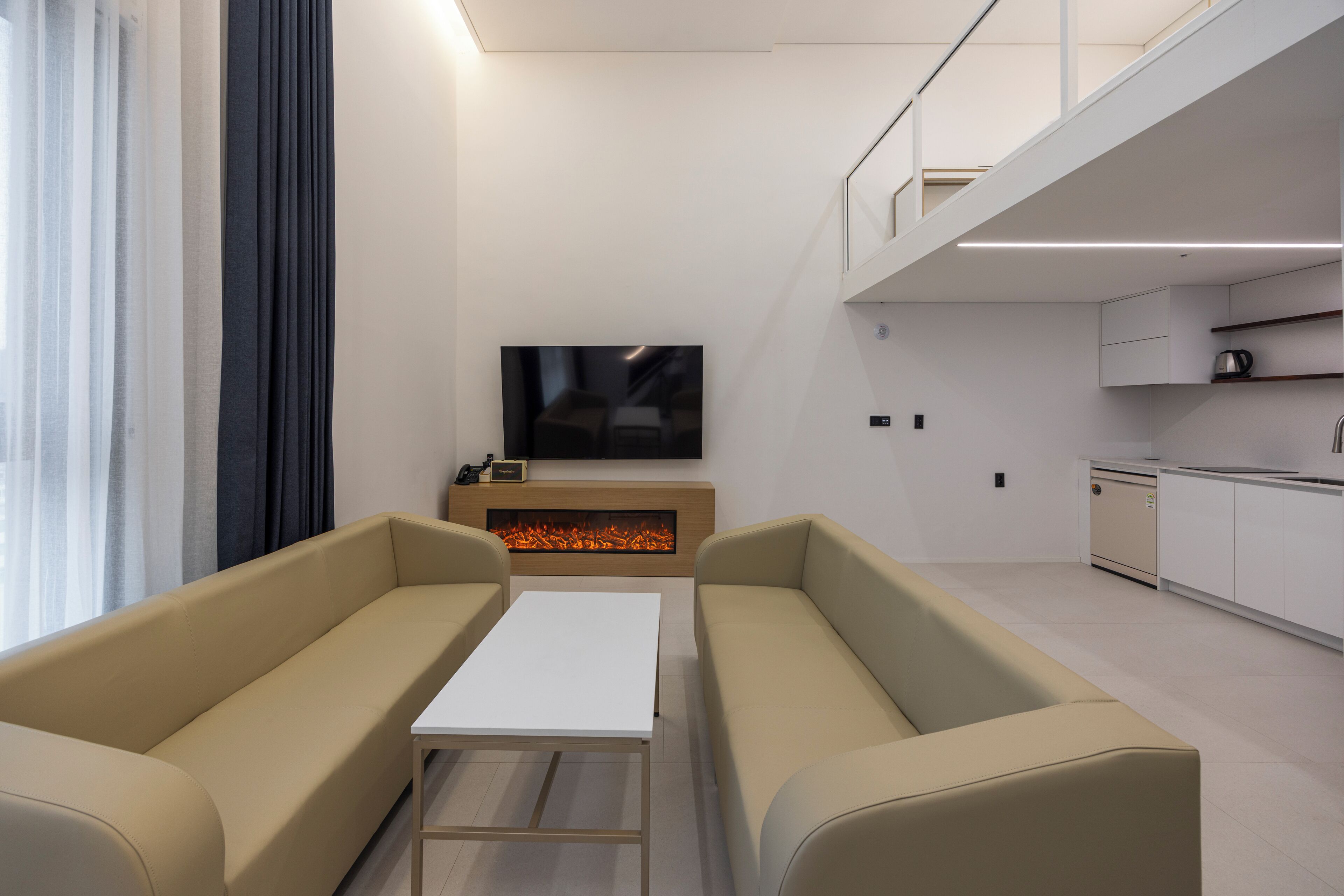 A modern living room with a sofa set, a flat-screen TV, and a fireplace.