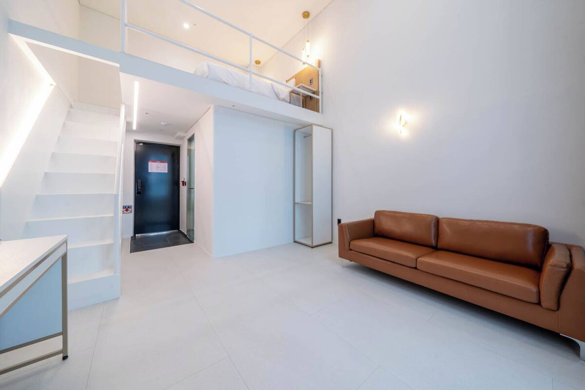 A modern interior with a staircase, a sofa, and a desk.