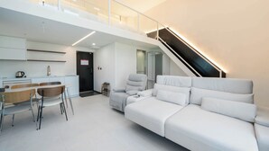 Un espace de vie moderne et minimaliste comprenant un canapé, une table à manger, des chaises et un escalier.