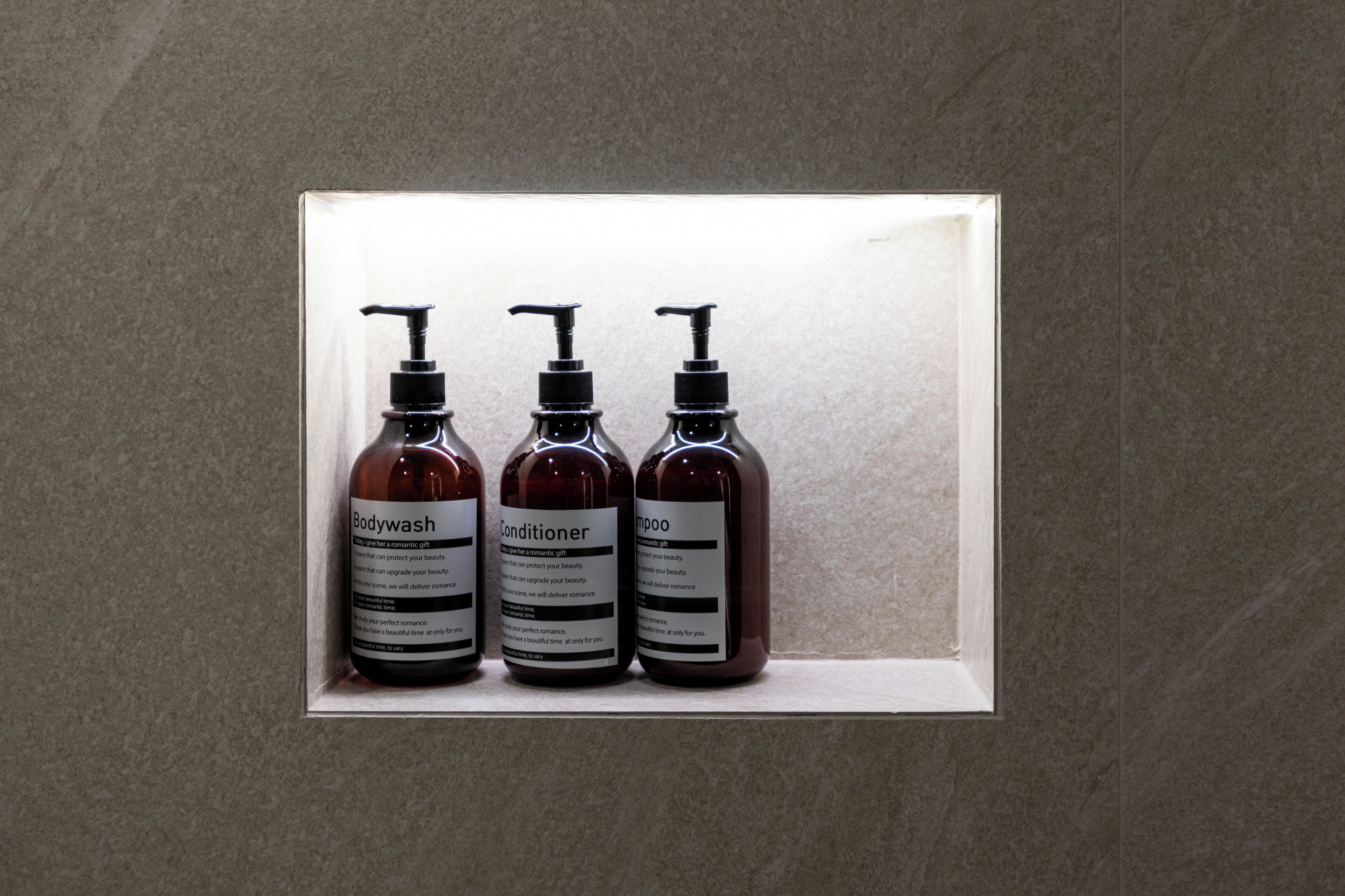 Tres botellas de gel de baño, acondicionador y champú en una presentación decorativa.