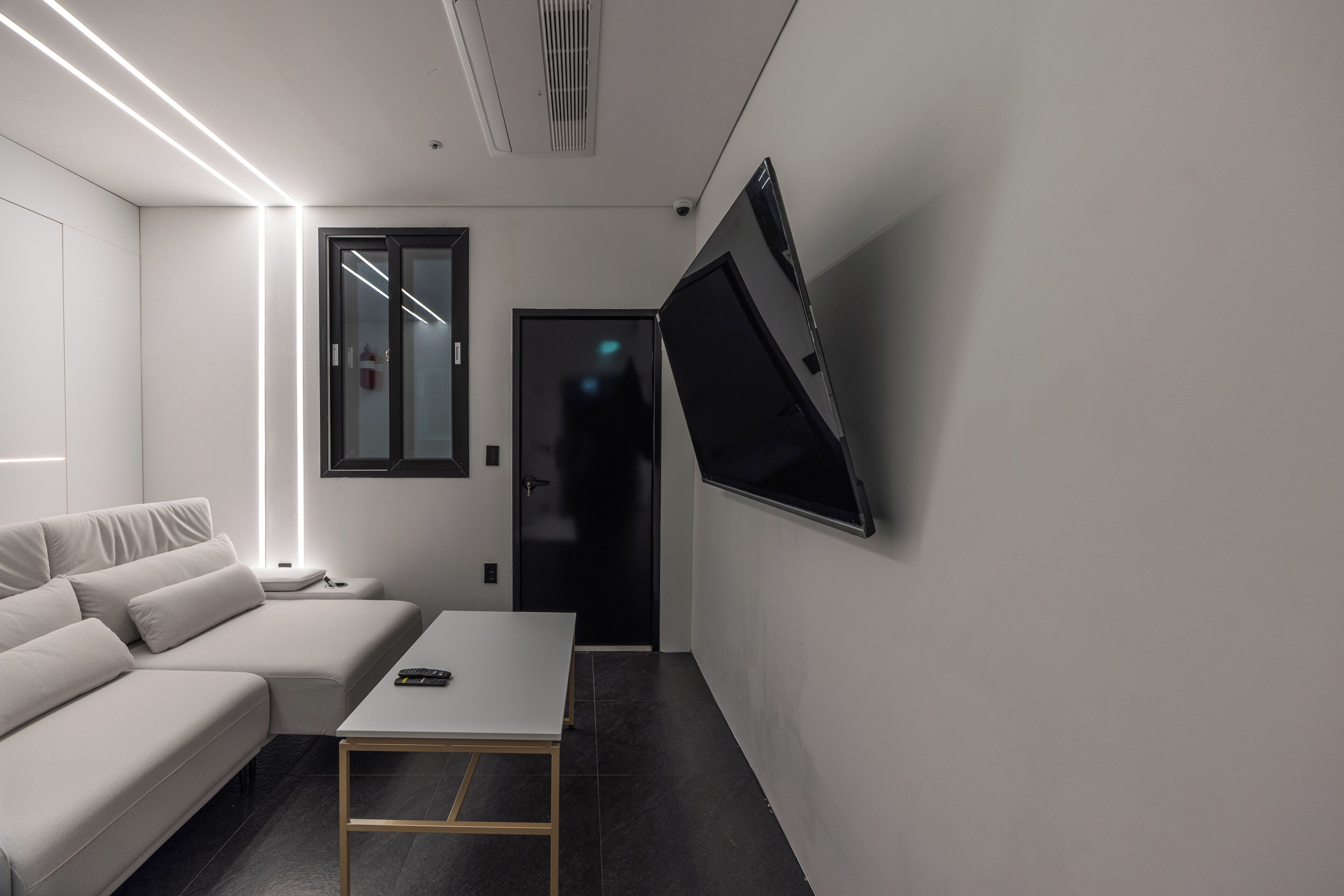 A modern living room with a sofa, a coffee table, and a flat-screen TV mounted on the wall.