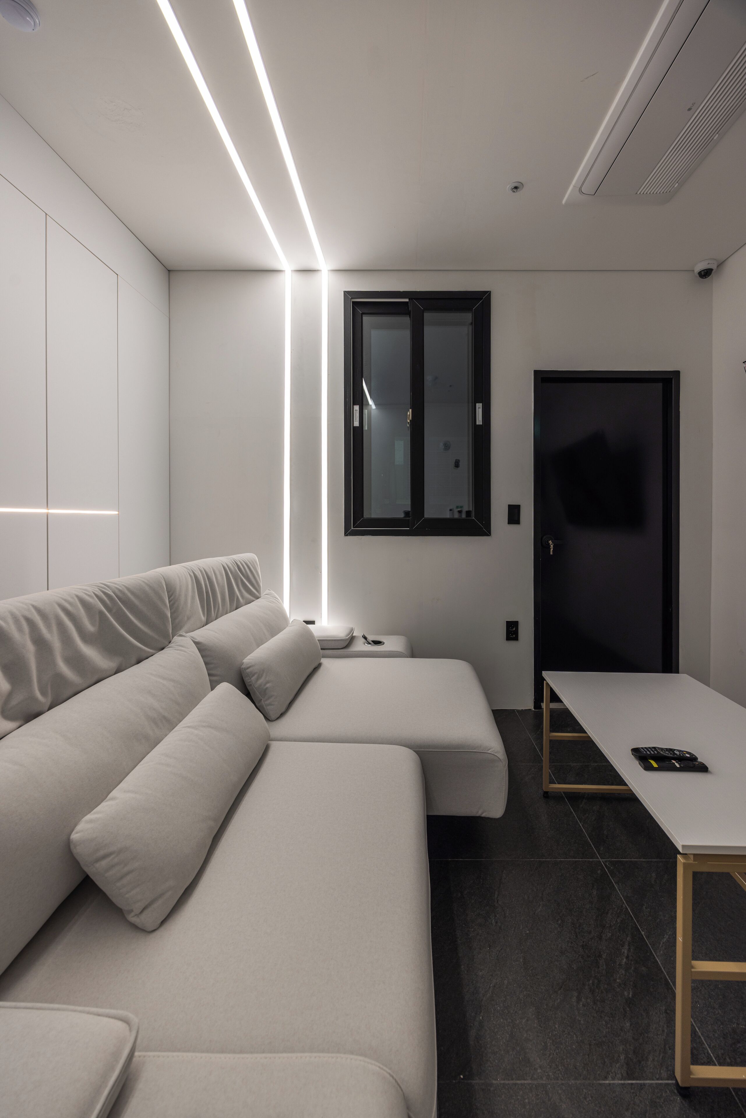 Une pièce moderne et minimaliste, avec un canapé, une petite table et un téléviseur fixé au mur.