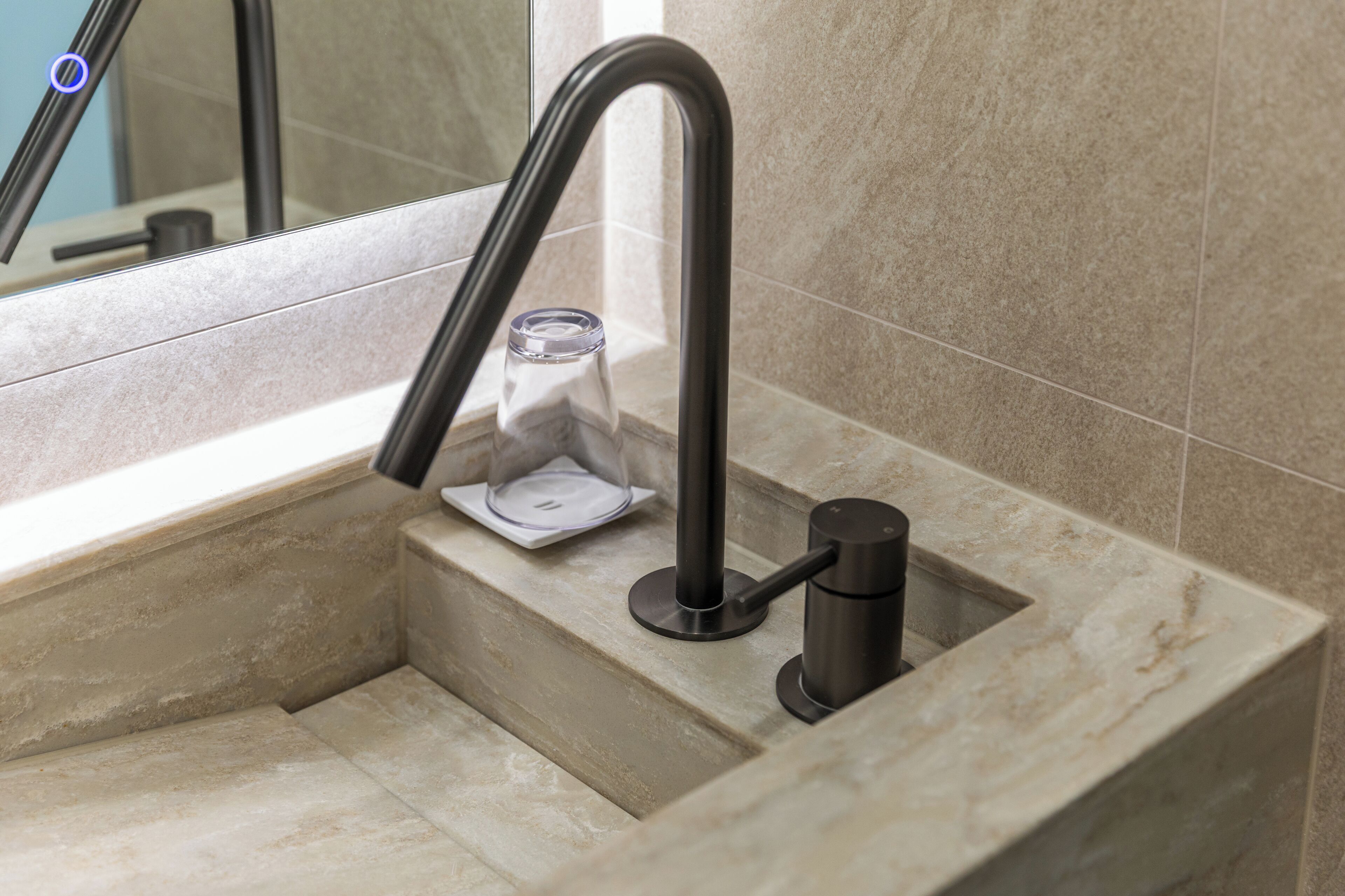 A bathroom with a modern sink, a glass soap dish, and a towel rack.