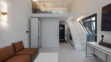 A modern interior with a sofa, a desk, a staircase, and a TV.