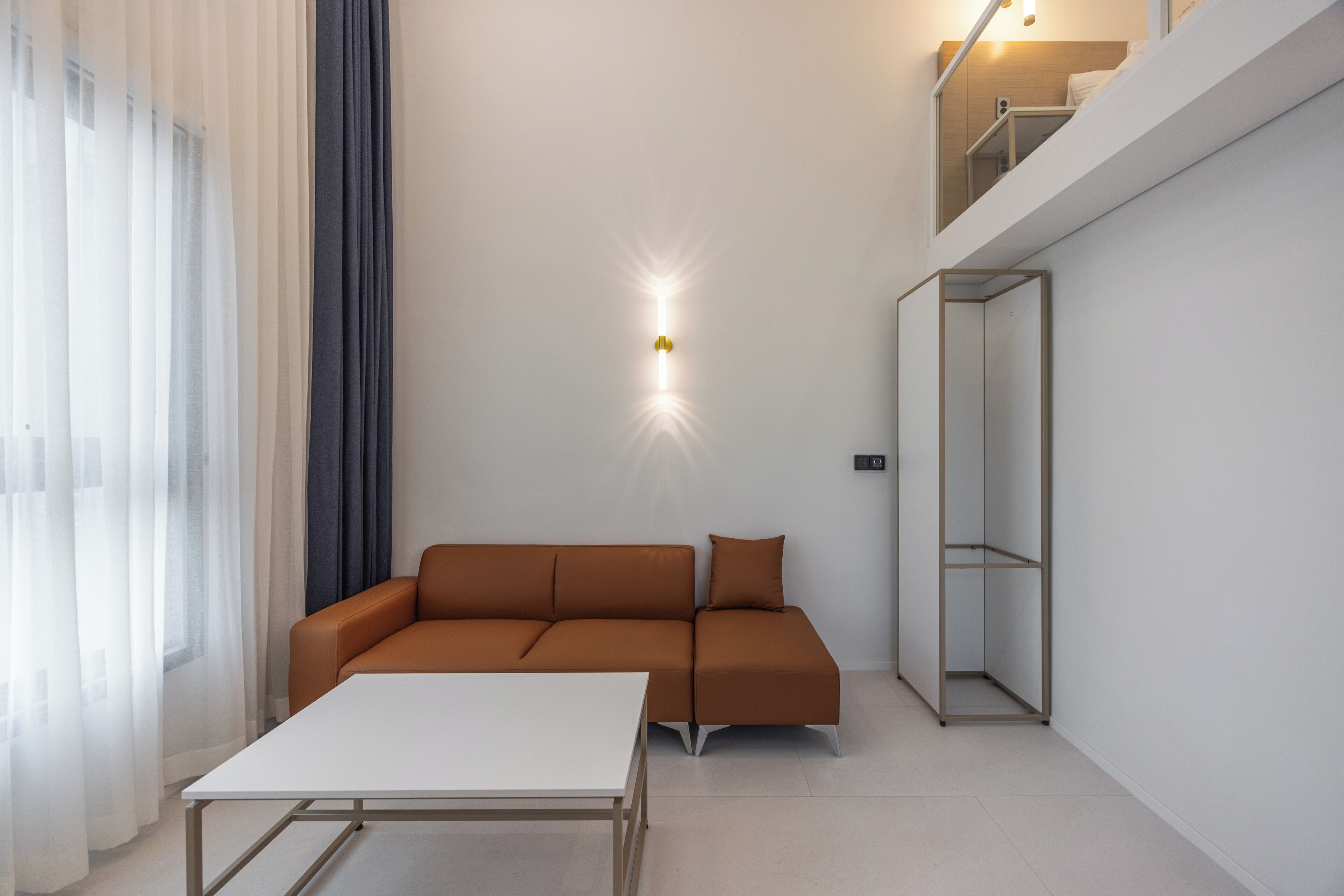 A modern living room with a brown sofa, a white coffee table, and a glass cabinet.