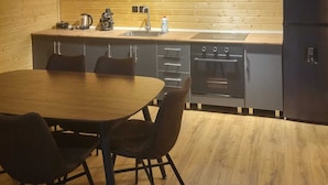 Una cocina compacta con una mesa y sillas, horno empotrado y refrigerador.