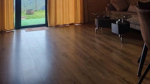 Un interior de madera con un sofá, una mesita de centro, una puerta que da a vistas de la montaña y una lámpara en el techo.