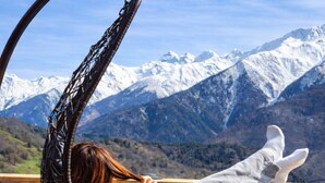 A person relaxing in a hanging chair with a mountain view. - Svanieri cozy cottage in the mountains (Mestia Municipality)