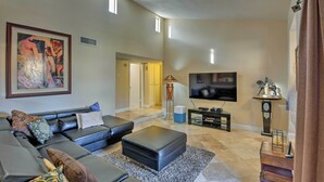 Een moderne woonkamer met een modulaire bank, een flatscreen televisie en een groot abstract schilderij aan de muur.