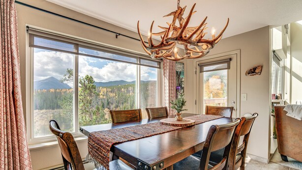 Un comedor con mesa de madera, sillas y una araña.