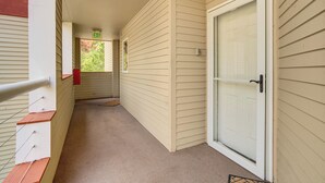 Un pasillo con paredes de revestimiento color beige, una puerta blanca con panel de vidrio y un buzón rojo.