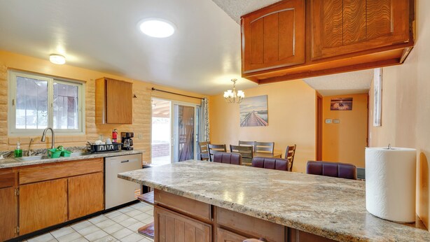 Una cocina con armarios de madera, encimera de granito, un lavabo y una zona de comedor con sillas y una mesa.