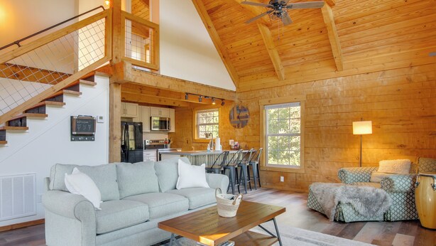 A spacious living area with a high ceiling, wooden beams, a staircase, a kitchen, and a dining area. - Hike & Unwind, Peaceful Wooded Retreat in Newport (Newport)