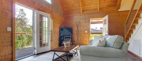 Un salón espacioso con techo de madera, chimenea, sofá y un ventanal grande.