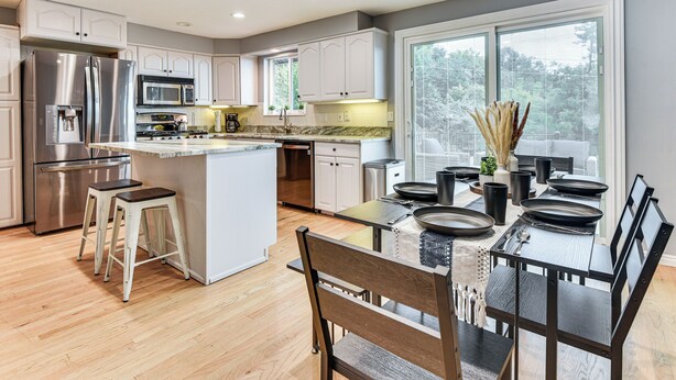 A modern kitchen with white cabinetry, stainless steel appliances, and a dining area with a glass table and black chairs. - Mountain-view Retreat w/ Hot Tub in Centerville! (Centerville)